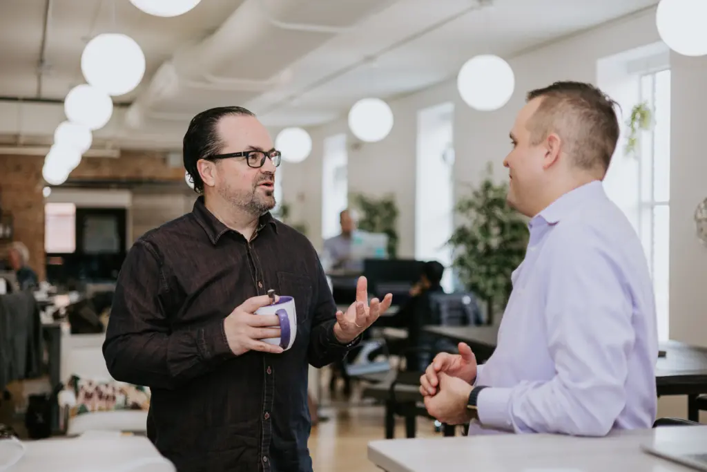 Guide to High Potential Mentoring Programs 6 Two men talking about high potential mentoring programs in an office.