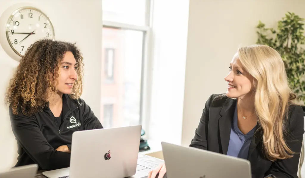 What Is an Employee Value Proposition? 7 Two female employees chat in an office with computers open.